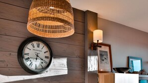 Un coin repas avec un mur en bois, une horloge et un luminaire suspendu.