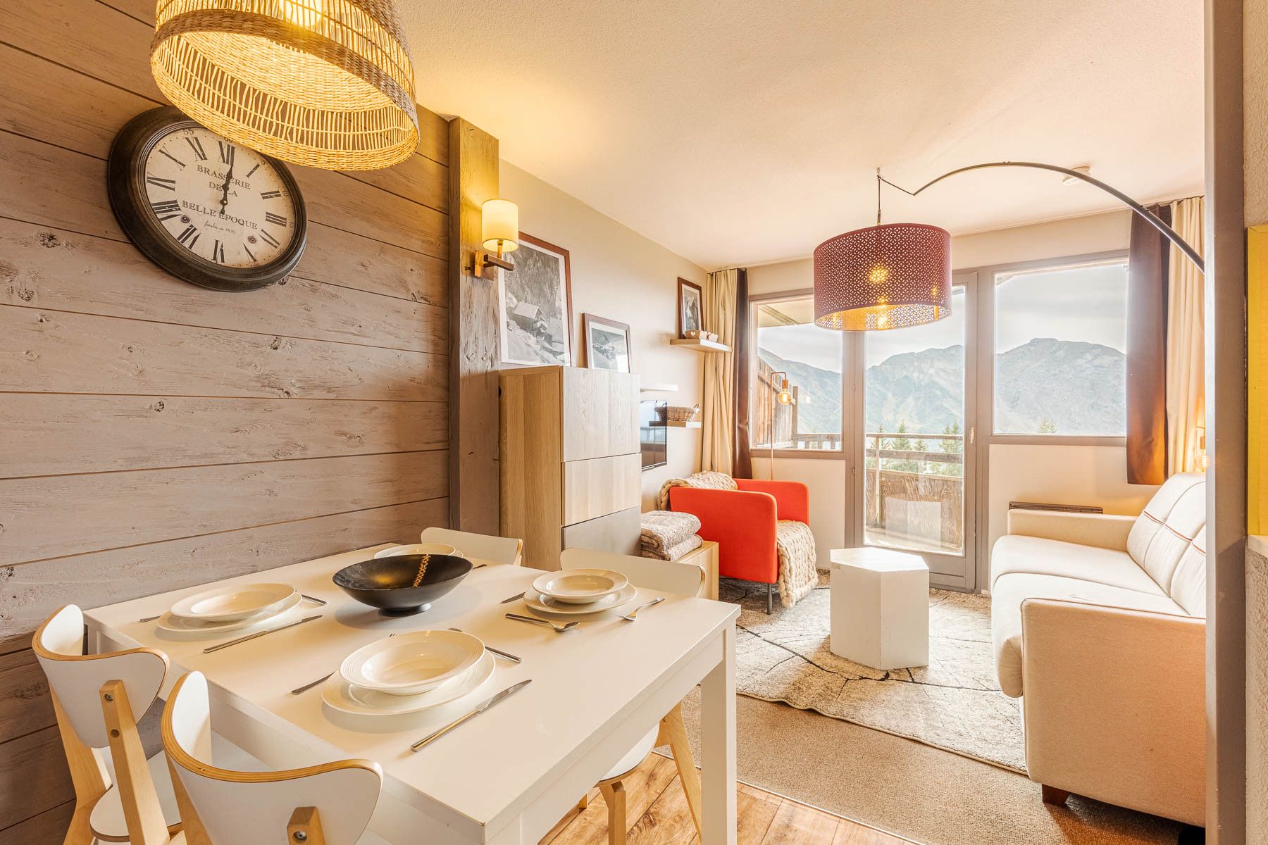 A modern interior with a dining area, a sofa, and a view of the mountains.