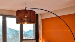 Une chambre dotée d’un grand lit, offrant une vue sur les montagnes par la fenêtre, et présentant un design original avec un mur incurvé.