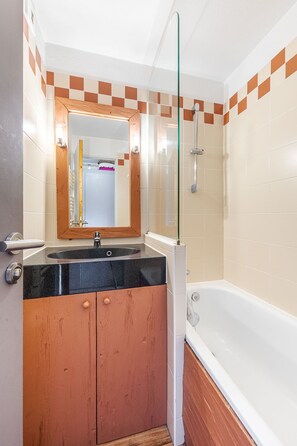 Een badkamer met een bad, een wastafel en een spiegel.