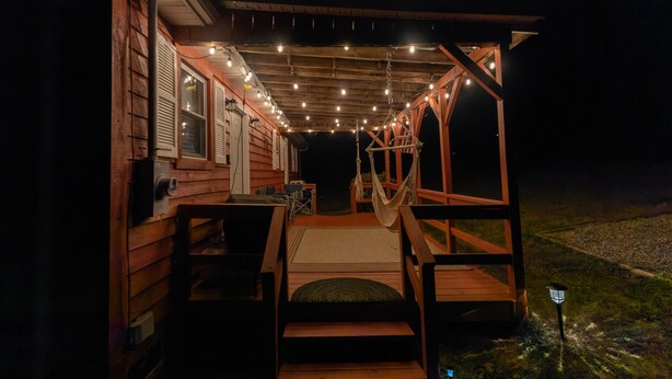 Eine Holzhütte mit Veranda, Lichterketten und einer Hängematte.
