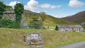 Um arco de pedra com uma placa de boas-vindas, um edifício de pedra e uma estrada.
