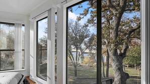 Una habitación con ventanas amplias, una cama y vistas a árboles y un parque.