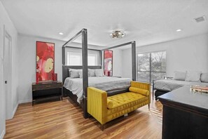 A bedroom with a four-poster bed, a yellow armchair, and a nightstand with a lamp. - Huge Lakefront Getaway Hot Tub, Deck, Sleeps 16 (Little Elm)