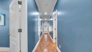 A hallway with blue walls, wooden flooring, and white doors. - Eden Guest House on Bayfront Mansion Estate. A 3/3! 20 scenic minutes to Destin (Freeport)