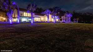 A two-story house with a well-lit front yard and palm trees. - Eden Guest House on Bayfront Mansion Estate. A 3/3! 20 scenic minutes to Destin (Freeport)