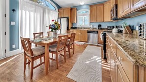 A kitchen with wooden cabinets, a dining table with chairs, a refrigerator, and a window with blinds. - Eden Guest House on Bayfront Mansion Estate. A 3/3! 20 scenic minutes to Destin (Freeport)