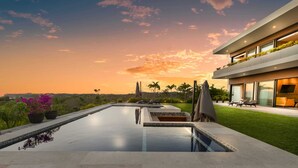 Une maison moderne dotée d’une piscine, de mobilier d’extérieur et offrant une vue sur le coucher de soleil.