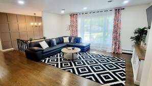 Una sala de estar moderna con un sofá modular, una mesa redonda de centro y una alfombra estampada.