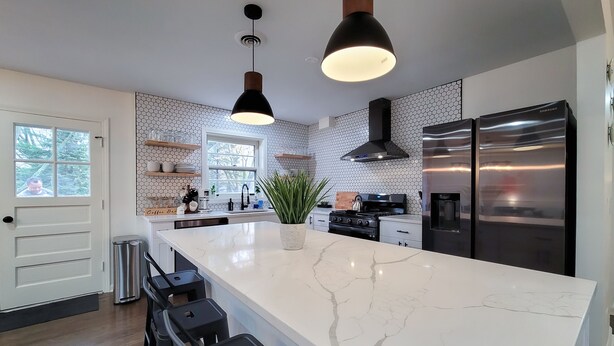 Una cocina moderna con una isla grande, electrodomésticos de acero inoxidable y un salpicadero con diseño hexagonal.