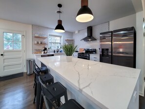 Una cocina moderna con una isla grande, electrodomésticos de acero inoxidable y un salpicadero con diseño hexagonal.