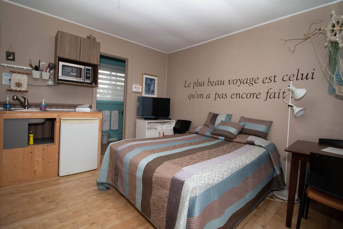 Une chambre compacte comprenant un lit, un bureau, un four à micro-ondes et un petit réfrigérateur.