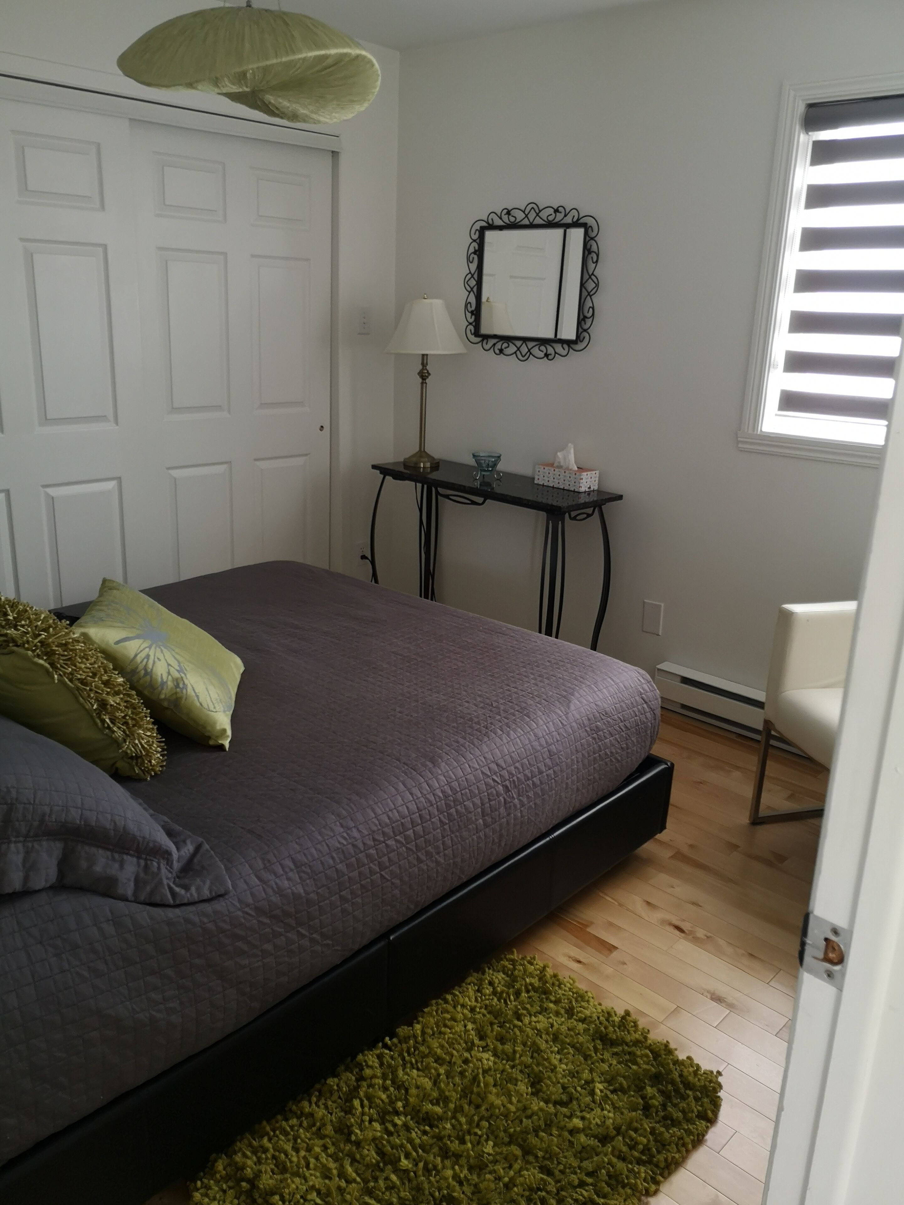 Une chambre à coucher avec un lit, un bureau, une chaise, une fenêtre et une porte.