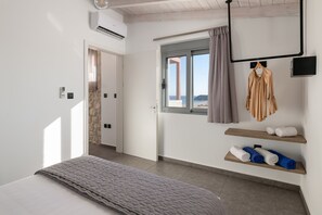 A hotel room with a bed, a window with a view, a hanging towel rack, and a wall-mounted TV.
