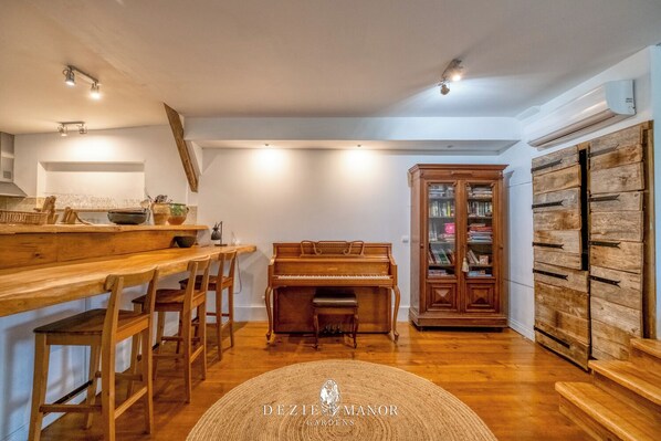 A cozy kitchen with wooden furniture, a piano, and a bookcase.