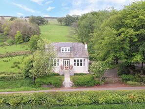 A white cottage with a stone staircase leading to a wooden door, surrounded by lush greenery and a fenced garden. - 3 bedroom accommodation in Girvan (Girvan)