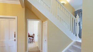 A staircase with white balusters leading to a landing, a door on the left, and a chair in the background. - 3 bedroom accommodation in Girvan (Girvan)