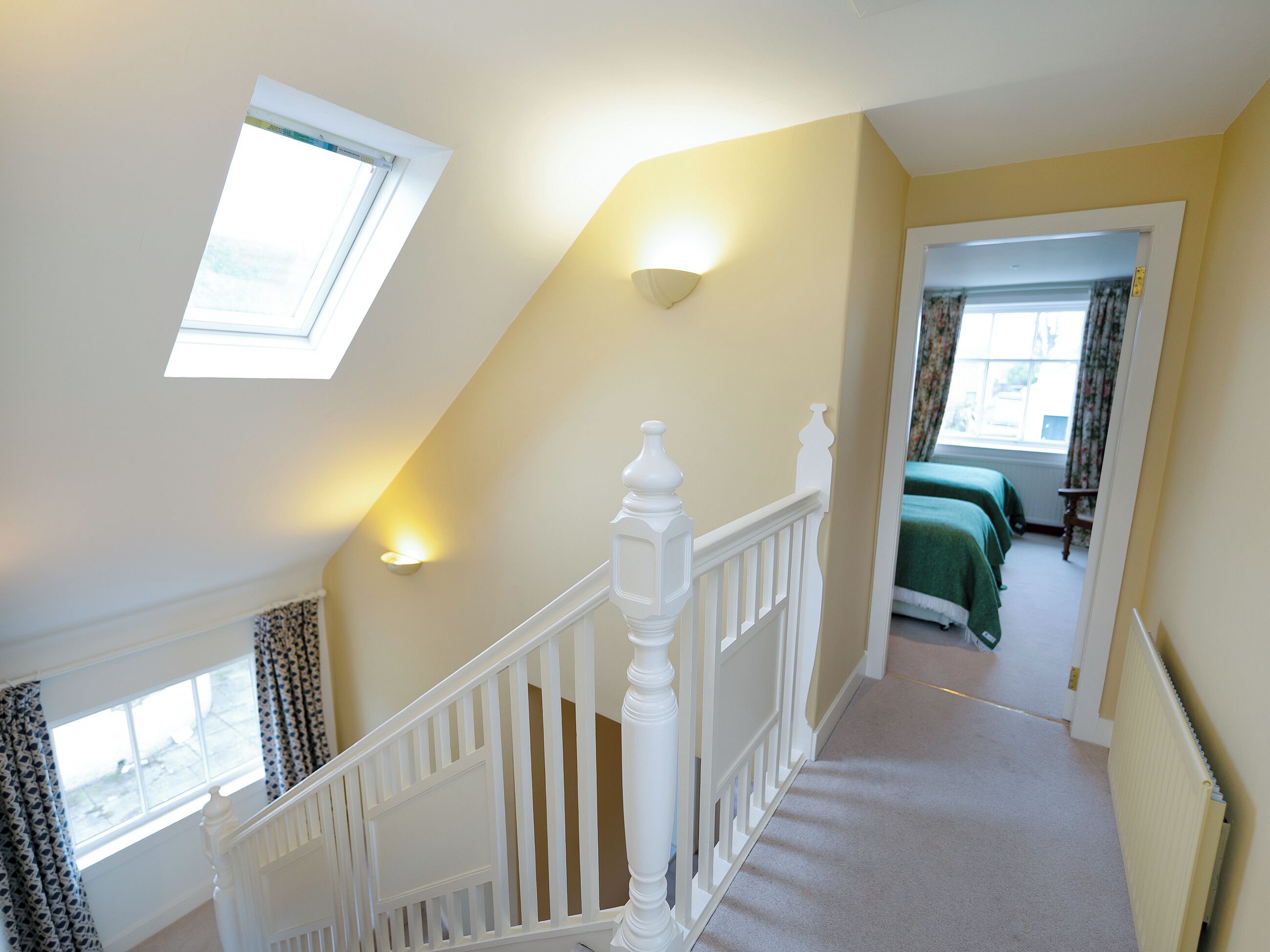 A staircase leading to a bedroom with a skylight and a view of the outside.