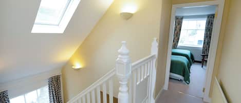 A staircase leading to a bedroom with a skylight and a view of the outside.