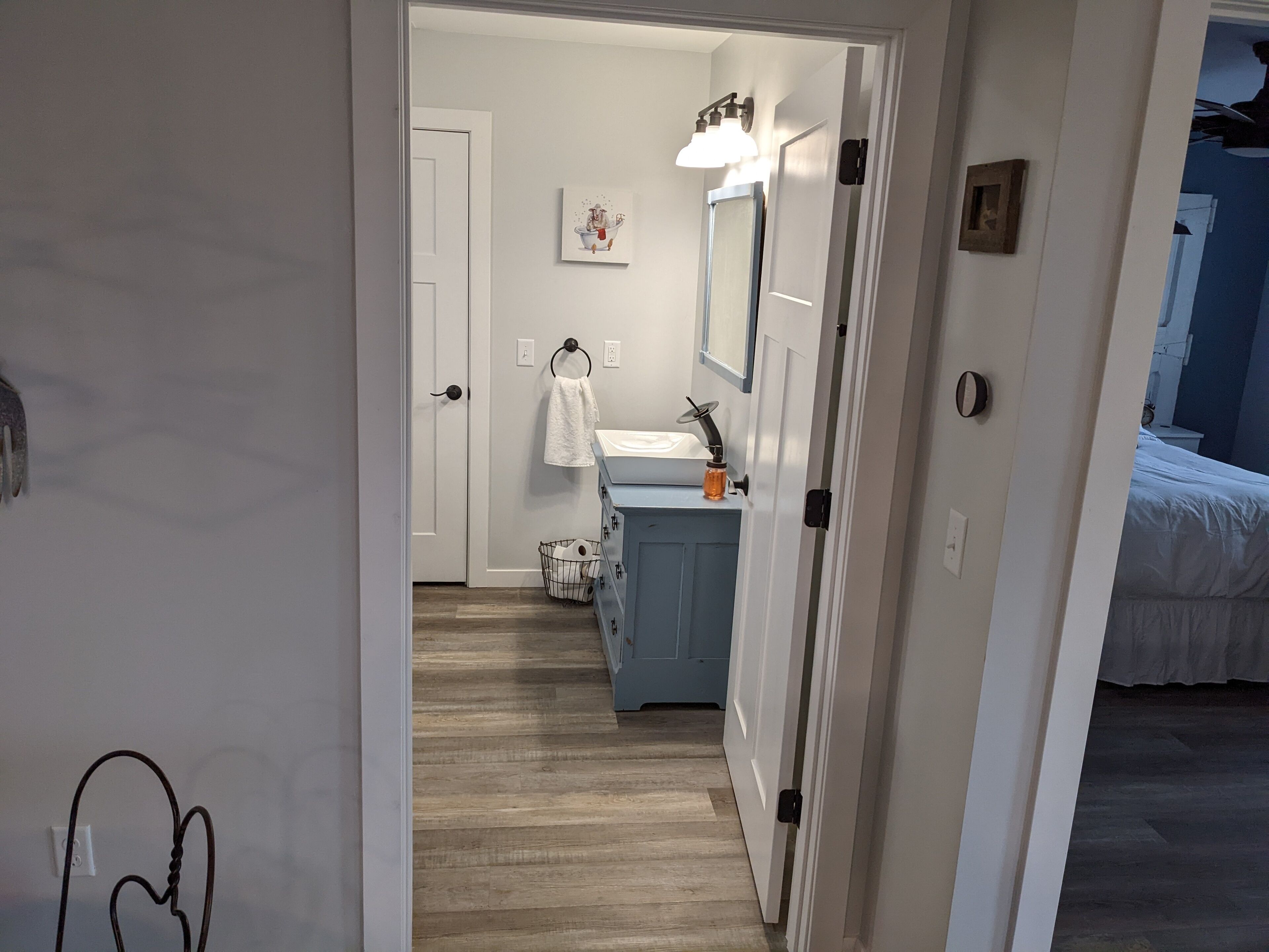 A hallway leading to a bathroom with a sink, mirror, and towel rack.