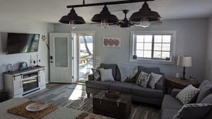 A modern living room with a grey sofa, a coffee table, and a TV mounted on the wall.