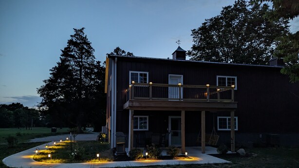 A two-story house with a balcony, a porch, and a well-lit driveway.