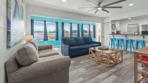 A modern living room with a sofa, a coffee table, and a ceiling fan. - Tranquil Tortuga *Lake View* Heated Pool (Destin)