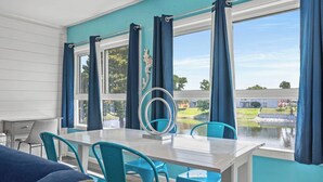 A dining area with a table and chairs, a view of a body of water, and a decorative mirror. - Tranquil Tortuga *Lake View* Heated Pool (Destin)