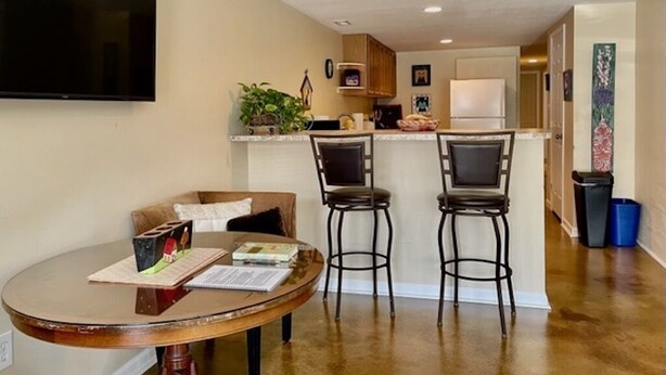 A compact living space with a dining area, kitchen, and a TV mounted on the wall.