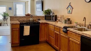 A kitchen with wooden cabinets, a stove, a microwave, and a sink.