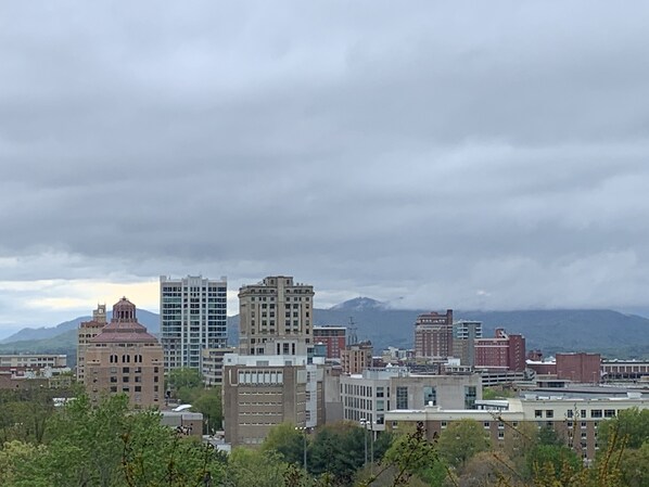A cityscape with various buildings, including a mix of modern and older architecture, under a cloudy sky.