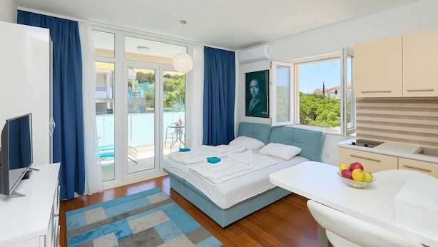 A modern bedroom with a bed, a desk, and a kitchen area. - Studio LINO in Solitudo (Dubrovnik)