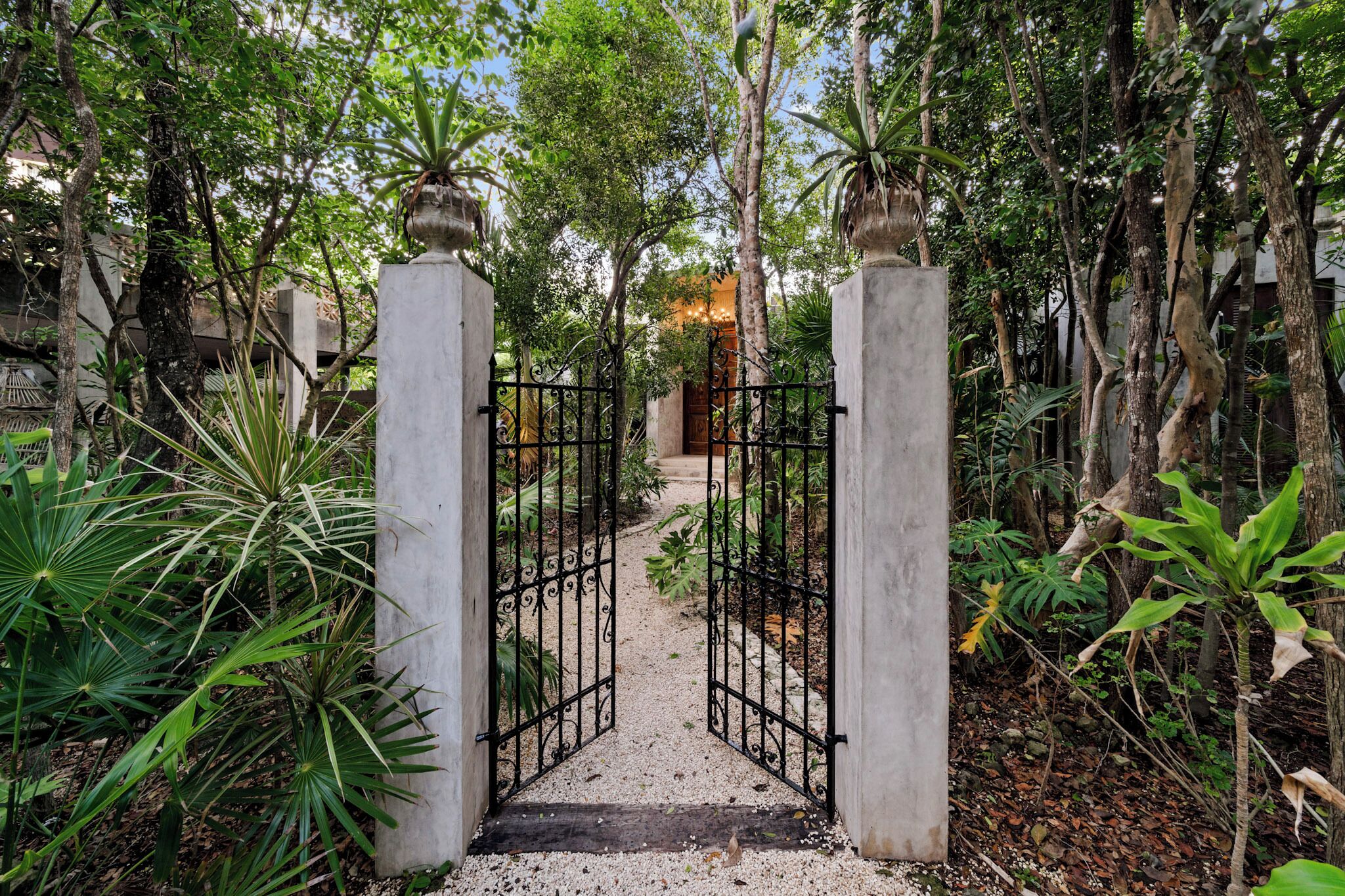 A gated entrance with a gravel path leading through a lush garden area.