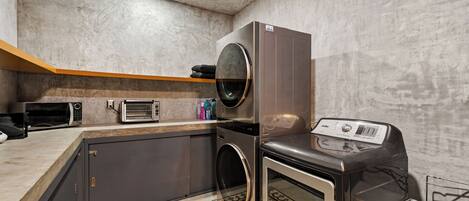 A compact kitchen with a built-in washer, a microwave, a toaster, and a small oven.