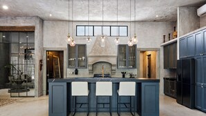 A modern kitchen with a central island, bar stools, pendant lighting, and built-in cabinets. - Casa Halo - Mansion, Nightclub, Pool, Gated, Staff (Tulum)