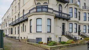 Un immeuble d’angle doté de nombreuses fenêtres, de balcons et d’un escalier menant à l’entrée.