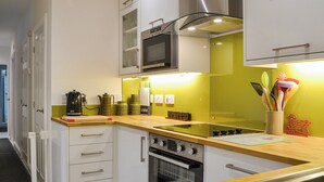 Une cuisine moderne avec des armoires blanches, une hotte de cuisinière en acier inoxydable et un plan de travail en bois.