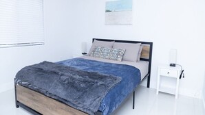 A modern bedroom with a bed, bedside tables, and a window.