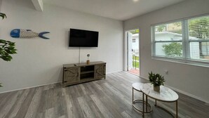 Una sala de estar moderna con un televisor de pantalla plana montado en la pared, un mueble de entretenimiento de madera y una mesa de centro redonda.