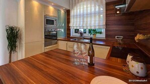 Uma cozinha moderna com bancadas de madeira, fornos embutidos e uma janela grande com cortinas.