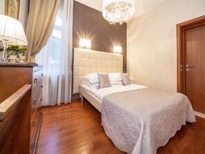 Ein Schlafzimmer mit Bett, Nachttisch, Kommode, einer Kandelaber und einer Tür.