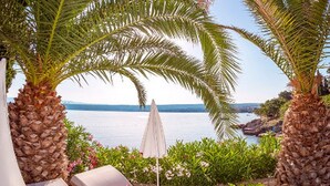 Uma área externa ensolarada com cadeiras de lounge e vista para o mar.