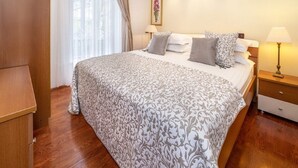 Ein Hotelzimmer mit einem großen Bett, einem Nachttisch, einer Lampe, einem Bild an der Wand und einem Fenster mit Vorhängen.
