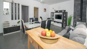 Een moderne woonkamer met een eethoek, een televisie en een open haard.