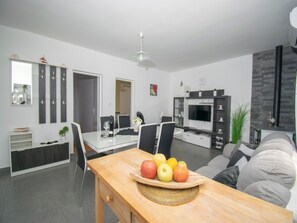 A modern living room with a dining area, a TV, and a fireplace.