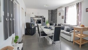 Een moderne woonkamer met een eethoek, een bank en een keuken op de achtergrond.