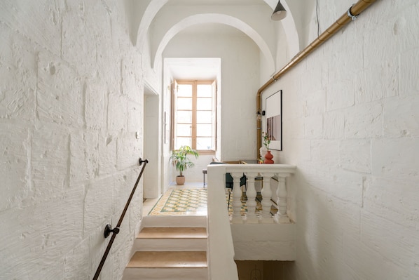 A staircase with white walls, a wooden floor, and a checkered tile at the bottom.
