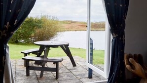 Une pièce avec vue sur un lac, une table en bois et un banc.