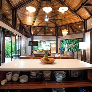 Una cocina amplia con una isla grande, vigas de madera en el techo y vistas al exterior.