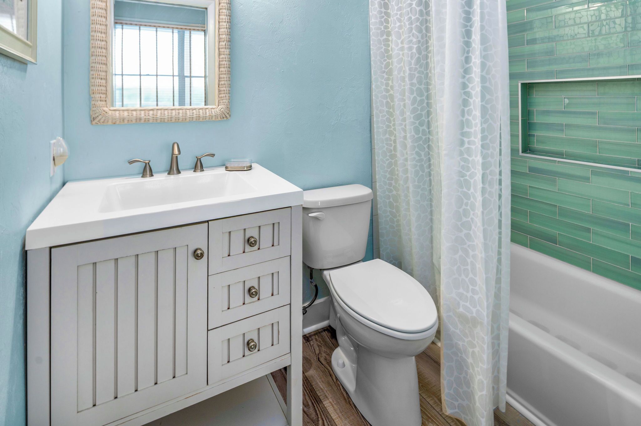 A bathroom with a white vanity, a toilet, and a bathtub.